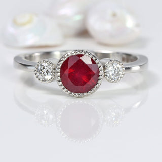 ruby and diamond trilogy engagement ring in platinum on grey surface
