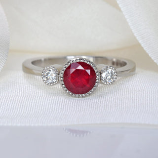 Natural red ruby and diamond trilogy engagement ring on white silk ribbon