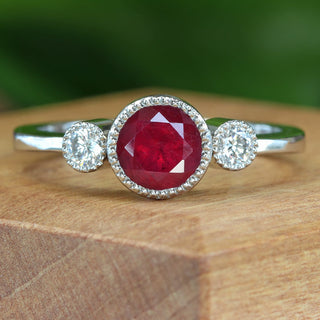 Platinum Ruby and Diamond trilogy engagement ring on wooden display