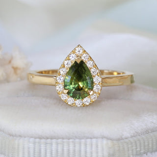 Pear cut green sapphire halo engagement ring with diamond halo styled with soft florals.