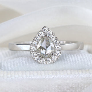 Pear cut rose diamond halo engagement ring photographed on pale fabric.