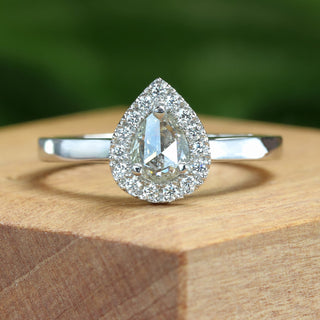 Pearl cut diamond halo engagement ring on wooden ring box.