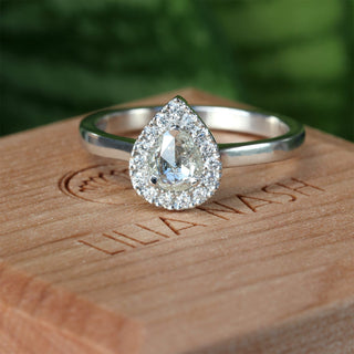 Platinum pear diamond halo engagement ring photographed outdoors.