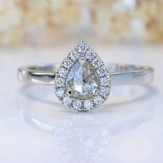 Handmade rose cut diamond halo engagement ring on white floral background.