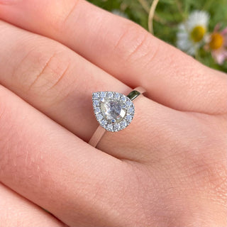 Platinum pear diamond halo engagement ring shown worn on hand.