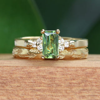 Emerald cut green sapphire and diamond cluster engagement ring with a wedding band hand engraved with lavender flowers