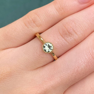 18ct gold green sapphire solitaire engagement ring shown on hand.