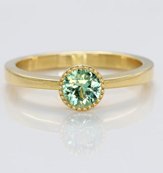 Handmade 18ct gold solitaire engagement ring with natural green sapphire in a milgrain bezel setting.