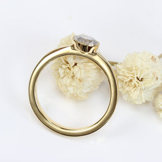 Gold salt and pepper diamond solitaire ring photographed against soft cream flowers.