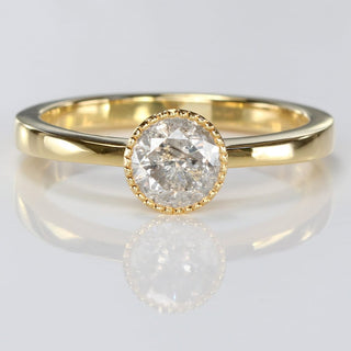 Handmade 18ct gold salt and pepper diamond solitaire ring with milgrain bezel on reflective surface.