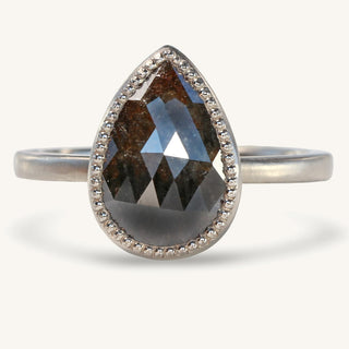 Handmade 18ct white gold solitaire ring set with a 2.10 carat pear cut black diamond in a bezel setting with milgrain detail. The band as a matte finish applied