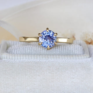 Natural unheated Ceylon sapphire engagement ring photographed on pale fabric.