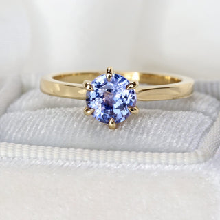 Handmade 18ct gold lavender sapphire ring photographed at an angle on pale fabric.
