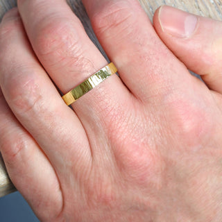Tree bark textured Men's 9ct gold wedding band, being worn on the hand