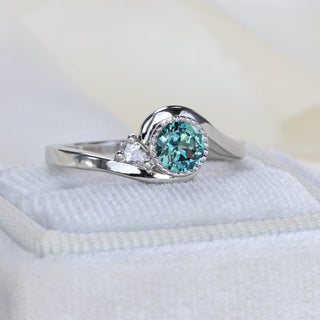 Side view of platinum teal Parti sapphire wave engagement ring showing curved band and bezel setting.
