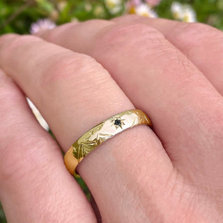 Solid 18ct gold black diamond 4mm court wedding ring for men with hand engraved mountains and stars. Displayed being worn on the hand