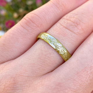 Sustainable 18ct gold 4mm court wedding band with hand engraved oak leaves and acorns around the band. Show being worn on the hand.