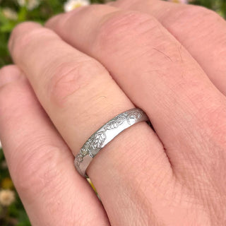 Sustainable solid 950 platinum 4mm court wedding ring with hand engraved oak leaf pattern. Shown being worn on a man's hand