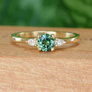 Fair trade green sapphire and diamond  18ct gold engagement ring on a wooden box with green background