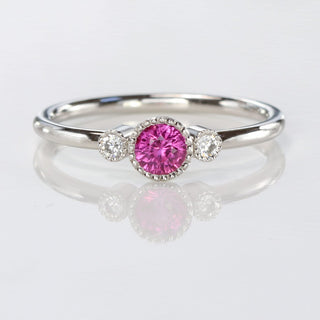 Pink sapphire petite platinum engagement rings with diamonds on a reflective background
