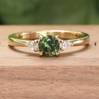 18ct gold Dark green sapphire and pear cut diamond engagement ring on a wooden box