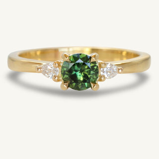Dark green sapphire trilogy engagement ring made from 18ct gold with pear cut side diamonds on a white background