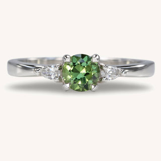 Platinum fair trade green sapphire  trilogy engagement ring with pear cut diamonds.