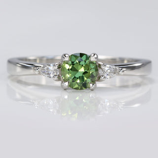 Platinum fair trade green sapphire  trilogy engagement ring with pear cut diamonds.