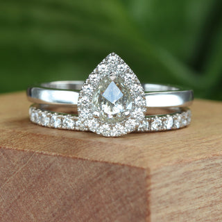 Close-up of pear diamond halo ring in platinum on wooden surface.
