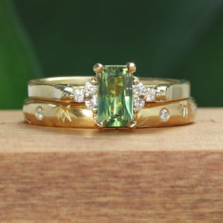18ct gold emerald cut Parti sapphire and diamond engagement ring with a hand engraved rising sun wedding band, on a wooden ring box