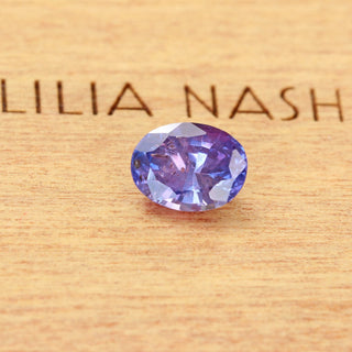 Natural oval purple sapphire displayed on Lilia Nash branded wooden background.