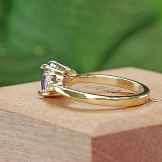 Oval purple sapphire engagement ring with pear cut diamonds photographed at an angle.