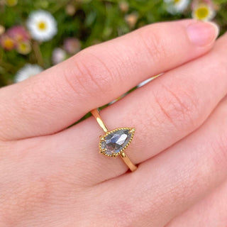 18ct gold rose cut salt and pepper diamond solitaire engagement ring in a bezel setting with milgrain detail. Displayed on the hand with daisies in the background