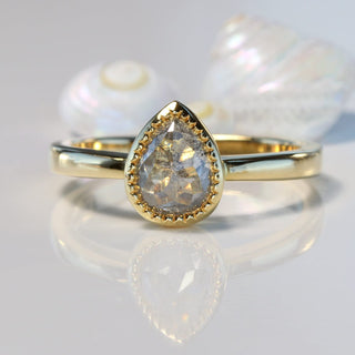Pear cut salt and pepper diamond solitaire 18ct gold ring on reflective surface