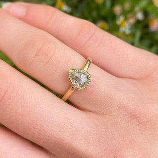 Pear cut salt and pepper diamond engagement ring worn on hand in 18ct gold.