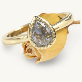 Pear cut salt and pepper diamond solitaire ring on orange rose bud