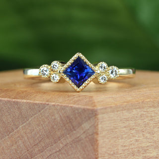 18ct gold sapphire and diamond cluster ring displayed on wooden surface.