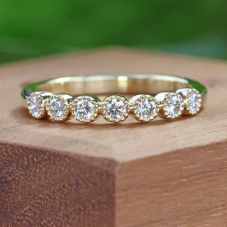 18ct gold seven diamond half eternity ring, handmade by Lilia Nash. On a wooden surface.