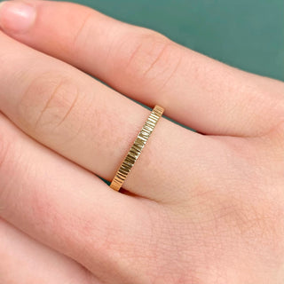 Slim 2mm hammered 9ct gold wedding band being worn in the finger