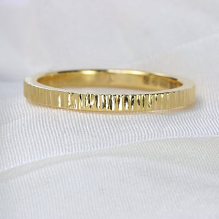 A slim 18ct gold wedding ring with a hammered tree bark texture, displayed on a white surface.