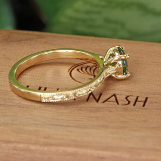 Side view of a green sapphire solitaire engagement ring, handmade from solid 8ct gold and featuring a hand engraved orange blossom pattern on the sides of the band