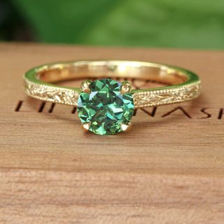 Fair trade green sapphire ring handmade from 18ct gold by designer Lilia Nash. With an engraved floral pattern on the band