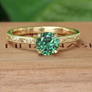 Green sapphire solitaire engagement ring in solid 18ct gold with hand engraved floral detail on the band