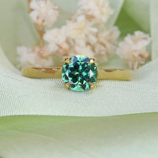 Handmade 18ct gold Parti sapphire solitaire engagement ring photographed on green fabric with white flowers