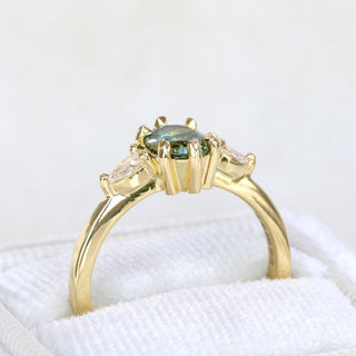 Angled closeup view of a 18ct gold oval Parti sapphire and pear cut diamond trilogy ring