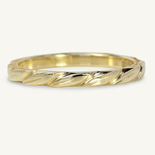 8ct gold leaves wedding band on a white surface with flowers
