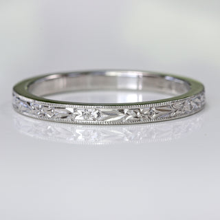 Close-up of the platinum wedding ring lying flat to display the engraved orange blossom design around the band.