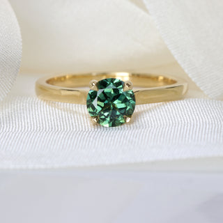 Parti sapphire solitaire engagement ring in 18ct gold photographed on pale fabric.