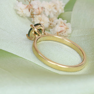 Close-up of Parti sapphire solitaire engagement ring in 18ct gold photographed on pale fabric.