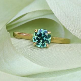 18ct gold solitaire engagement ring with Parti sapphire photographed on green fabric.